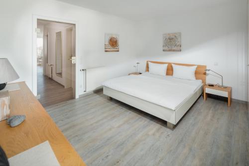 um quarto com uma cama branca e piso em madeira em Meerliebe em Norderney