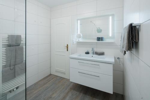 ein weißes Bad mit einem Waschbecken und einer Dusche in der Unterkunft Meerliebe in Norderney