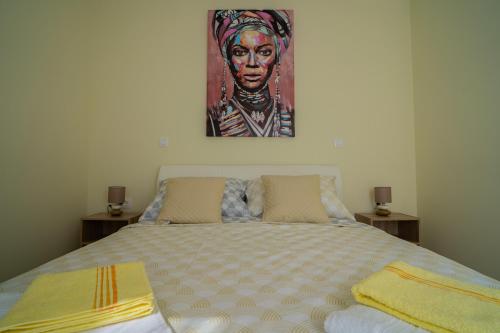 a bedroom with a bed with a painting on the wall at Laurel Apartments in Tisno