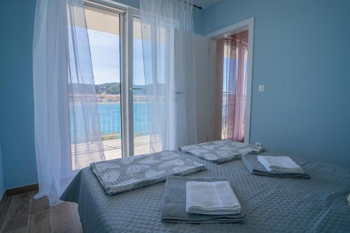 a bedroom with two beds and a large window at Laurel Apartments in Tisno
