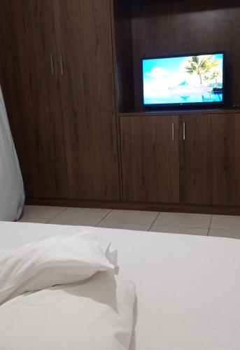 a bed with a white sheets and a tv in a room at Apartamento aconchegante in Ribeirão Preto