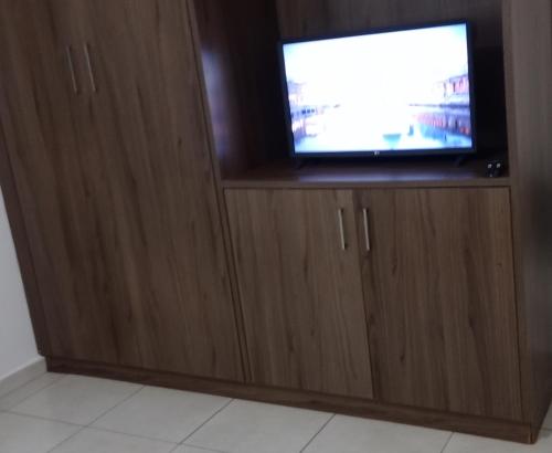 a tv in a wooden cabinet with a television at Apartamento aconchegante in Ribeirão Preto