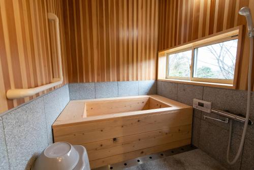 a wooden tub in a bathroom with a window at 鉢巻山荘 in Omura