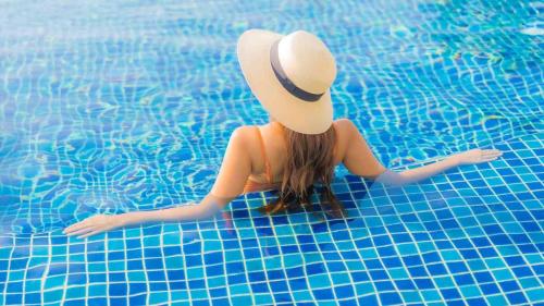 a woman in a hat sitting in a swimming pool at AYM Yoga Resort Arambol GOA in Arambol