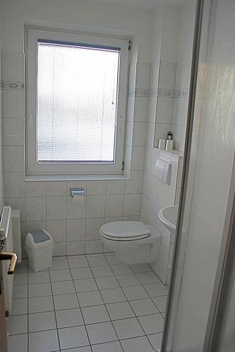 ein weißes Bad mit einem WC und einem Fenster in der Unterkunft Steife Briese in Dorum Neufeld