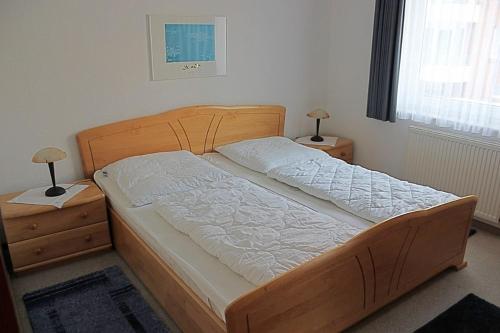 ein Schlafzimmer mit einem Holzbett mit zwei Nachttischen in der Unterkunft Steife Briese in Dorum Neufeld