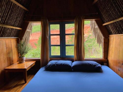 a bedroom with a blue bed and a window at Vườn Nhà Củi in Da Lat