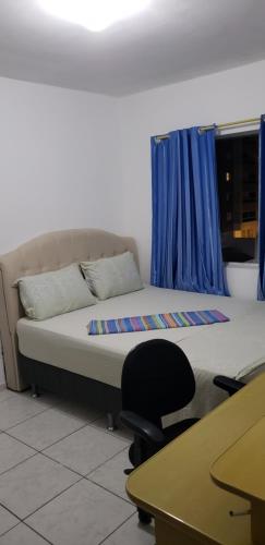 a room with a bed and a desk and a chair at Quarto em Apartamento Centro in Criciúma