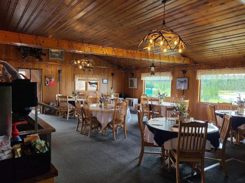 comedor con mesas y sillas y TV en Tolsona Lake Lodge, en Glennallen