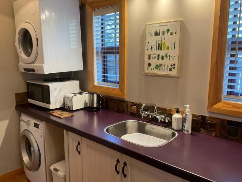 a kitchen with a sink and a microwave at Real Romance Cottage in Hanmer Springs