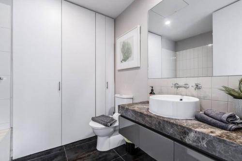 a white bathroom with a sink and a toilet at Amazing Luxury Apartment & so close to the CBD - 01756 in Melbourne