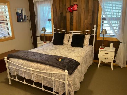 a bedroom with a white bed and two windows at Real Romance Cottage in Hanmer Springs