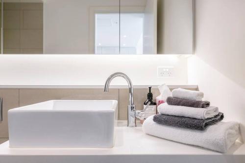 La salle de bains est pourvue d'un lavabo et d'un tas de serviettes. dans l'établissement Lovely 1 bedroom with free parking on premises - 00209, à Melbourne