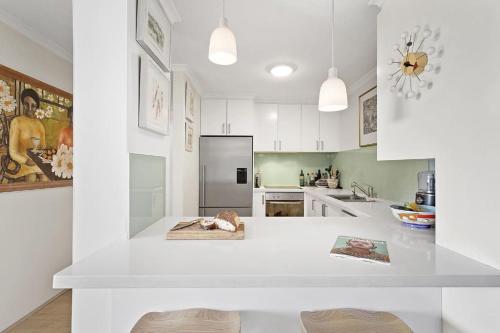 cocina con armarios blancos y encimera blanca en Impressive Centrally Located Penthouse, en Sídney