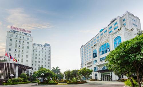 een groot wit gebouw met blauwe ramen en bomen bij Ninh Binh Legend Hotel in Ninh Binh