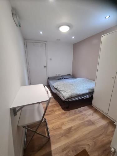 a small room with a bed and a table at Amazing 1 bed flat near Heathrow in Feltham