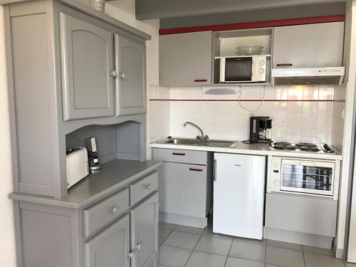 une cuisine avec des armoires blanches et des appareils électroménagers blancs dans l'établissement Maison de vacances près plage et commerces avec jardinet, parking privé et équipements complets - FR-1-22-165, à La Tranche-sur-Mer