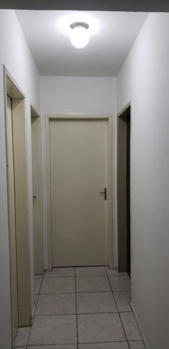 um corredor vazio com duas portas e um piso de azulejo em Quarto em Apartamento Centro em Criciúma