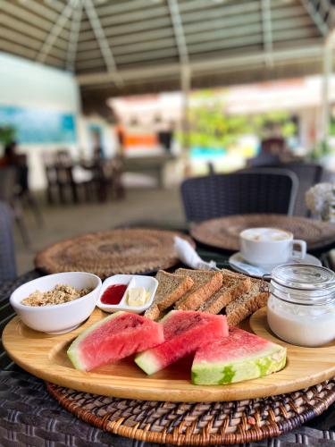 a plate of food with watermelon and bread on a table at Amihan Resort in Panglao