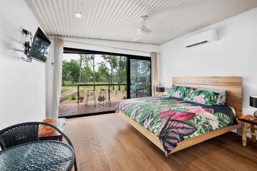 a bedroom with a bed and a sliding glass door at Litchfield Tropical Stay in Batchelor