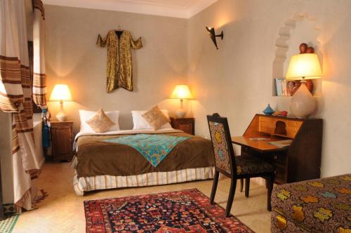 a bedroom with a bed and a desk and a cross on the wall at Riad Saba in Marrakesh