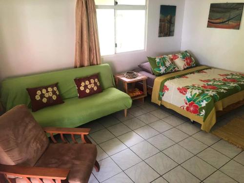 a living room with a green couch and a bed at VAIHEI 22 in Puahua