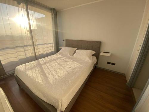 uma cama num quarto com uma grande janela em Céntrico Apartamento Frente al Metro em Santiago