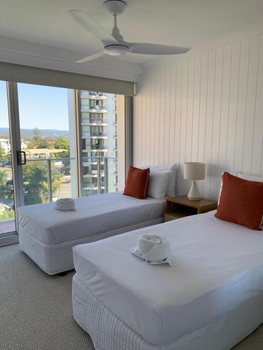 two beds in a room with a large window at Pacific Regis Beachfront Holiday Apartments in Gold Coast