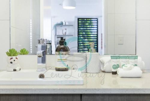 a bathroom counter with a sink with toiletries on it at ZEN NOMAD 2-BR Nightcliff Apt Near Markets & Shops in Nightcliff