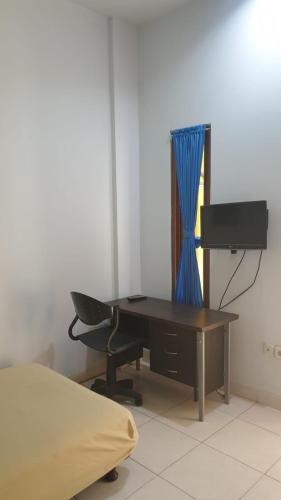 escritorio con silla y ordenador en la habitación en The Risen Kost, en Yakarta