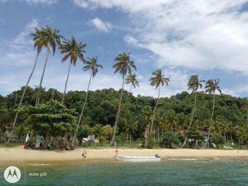 a boat on a beach with palm trees at Casa Amarela in Angra dos Reis