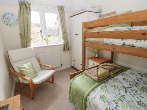 Glanton的住宿－Ramblers Cottage，一间卧室配有双层床和椅子
