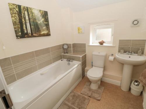 a bathroom with a tub and a toilet and a sink at Ramblers Cottage in Glanton