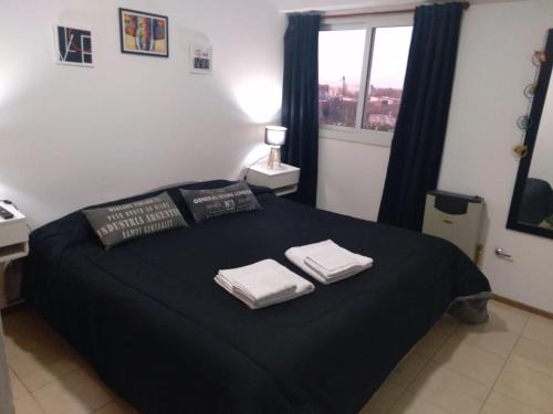 a bedroom with a black bed with two towels on it at PEUMAYEN ALOJAMIENTO TEMPORARIO en Trenque Lauquen in Trenque Lauquen