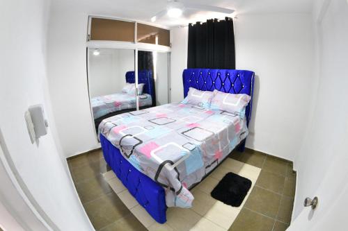 niebieskie łóżko w pokoju z lustrem w obiekcie las carreras centro D la ciudad w mieście Santiago de los Caballeros