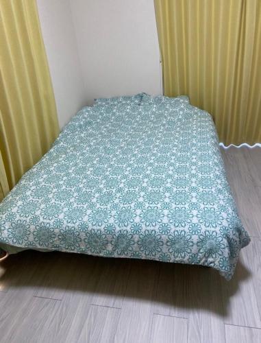 a bed with a blue blanket on a wooden floor at 勝浦 高台庭付き 星はとてもキレイ 鳥の鳴き声で目覚め 貸し切り in Katsuura