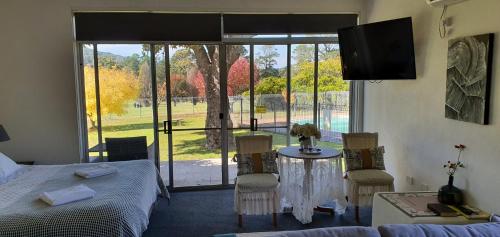 1 dormitorio con 1 cama, mesa y sillas en Golfview Lodge en Bowral