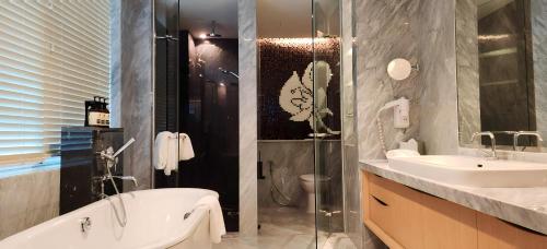a bathroom with a tub and a sink and a shower at Ascott Raffles Place Singapore in Singapore