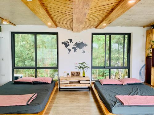 2 camas en una habitación con ventanas en LEE Garden - Venuestay, en Hanói