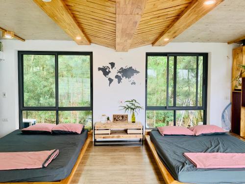 two beds in a room with windows at LEE & Sau Sau Garden - Venuestay in Hanoi