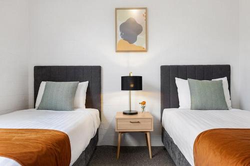 two beds sitting next to each other in a room at Oxley Court Serviced Apartments in Canberra