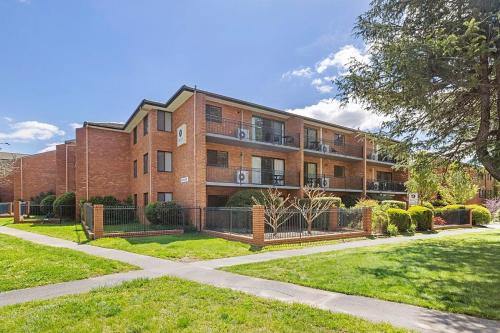 ein Backsteingebäude mit einem Zaun davor in der Unterkunft Oxley Court Serviced Apartments in Canberra