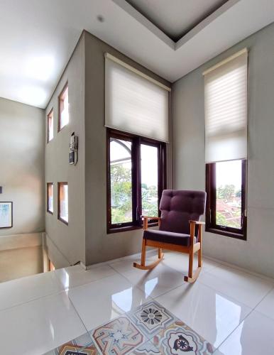 a living room with a chair and windows at SaBi Guest House - Strategic Family -married couples only- Hostel in Prawirotaman in Yogyakarta