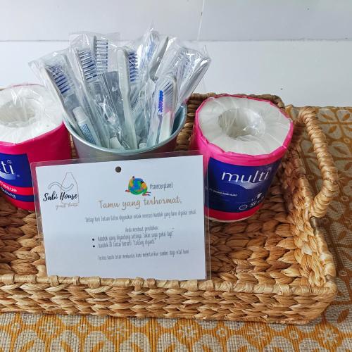 a basket with toothbrushes and a sign in it at SaBi Guest House - Strategic Family -married couples only- Hostel in Prawirotaman in Yogyakarta