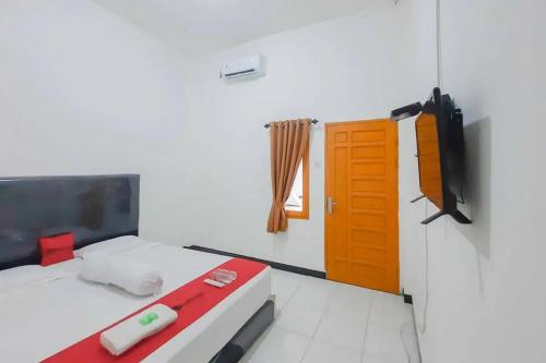 a room with a bed and a television and a door at RedDoorz at Permana Homestay near Supadio Airport Pontianak in Limbung