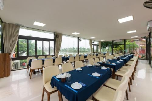 Sala bankietowa z niebieskimi stołami, krzesłami i oknami w obiekcie Tam Coc Sunshine Resort w mieście Ninh Binh