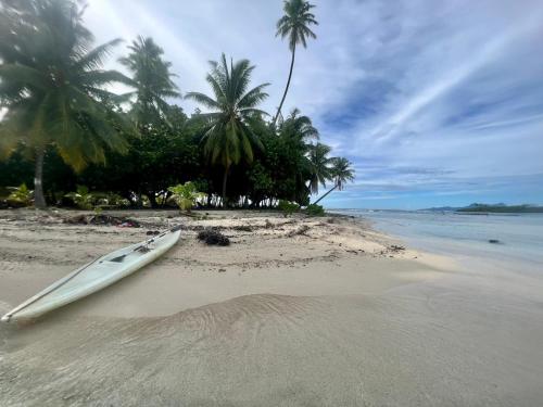a surfboard laying on a beach with palm trees at ROYAL Tapo-Tapo in Patio