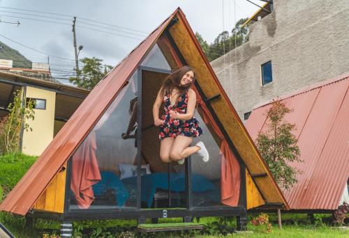 a woman is sitting in a triangular house at Hospedaje Campo Lago y Glamping in Otavalo