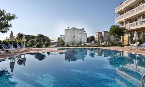 a large swimming pool with chairs and a building at Студио Симона 4 - първа линия море in Lozenets