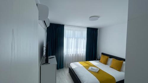 a bedroom with a bed with yellow and white pillows at APARTAMENT 2 CAMERE CENTRU ONESTI in Onești